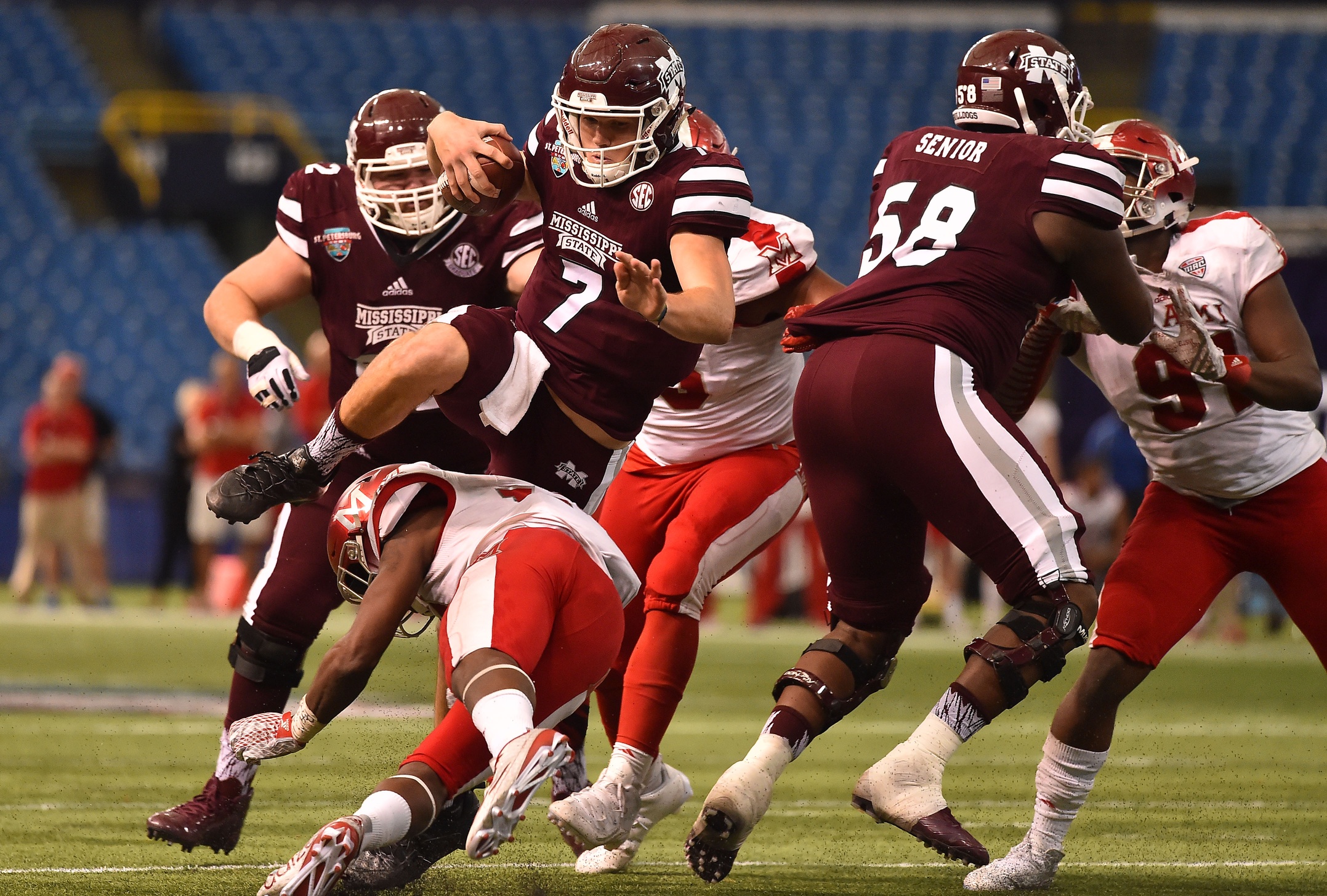 Dec 26, 2016; St. Petersburg, FL, USA; Mississippi State Bulldogs quarterback Nick Fitzgerald (7) jumps over Miami Redhawks defensive back Tony Reid (14) during the second half at Tropicana Field. The Mississippi State Bulldogs defeat the Miami Redhawks 17-16. Mandatory Credit: Jasen Vinlove-USA TODAY Sports