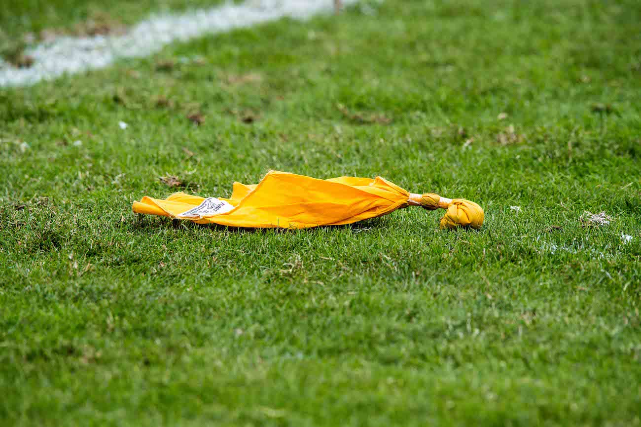 Yellow penalty flag sits on a grass field.