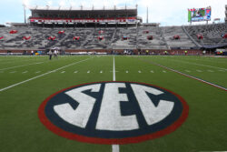 The SEC logo on a football field.