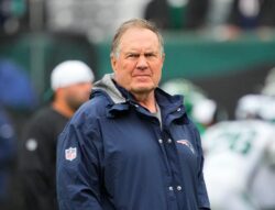 Bill Belichick stands on the field ahead of a game.