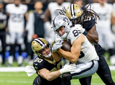 Brock Bowers is brought down by Saints defenders.