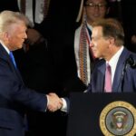 Donald Trump and Nick Saban shake hands.