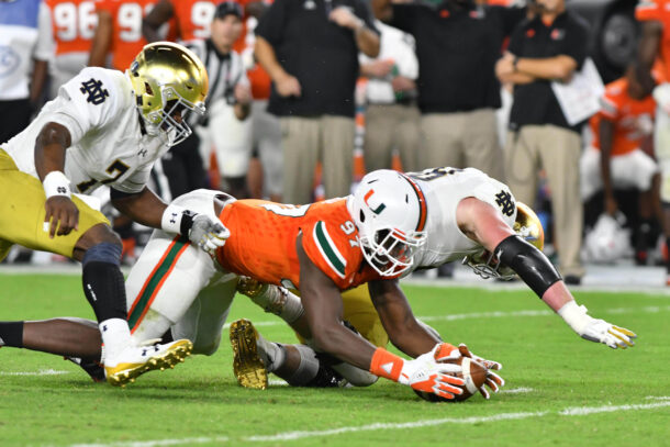 Notre Dame and Miami football players dive for a ball.