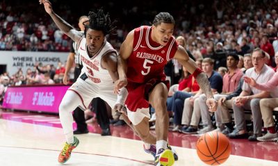 Darius Acuff Jr. of Arkansas battles an Alabama player for a loose ball.