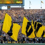 Iowa cheerleaders carry flags onto the field.
