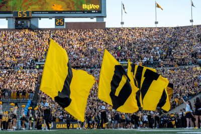 Iowa cheerleaders carry flags onto the field.